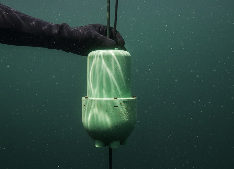 A diver holds a HYDRA buoy under water